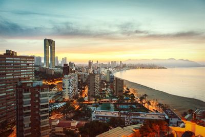 Idyllic view of benidorm against cloudy sky during sunset