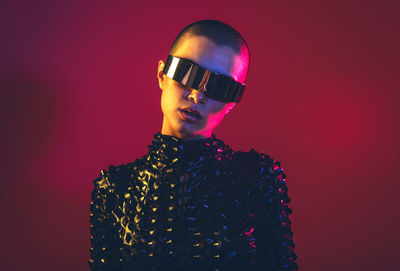 Young woman with shaved head against black background