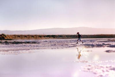 Full length of man walking on beach against sky