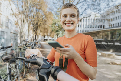 Portrait of smiling man holding bicycle on mobile phone