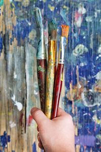 Cropped hand of child holding paintbrushes