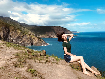 Portrait of young woman by sea against sky