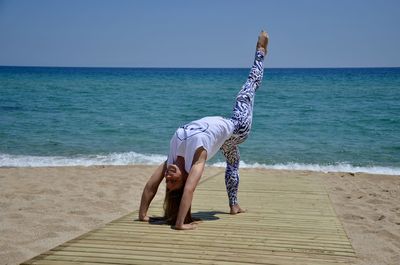 Woman on beach against sea against clear sky