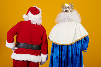 Rear view of woman standing against yellow background