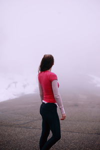 Rear view of young woman standing against sky