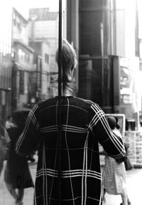 Rear view of woman standing against building in city