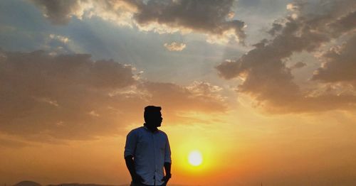 Silhouette man standing against sky during sunset