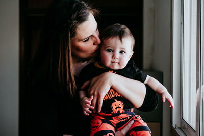 Portrait of daughter with mother sitting by window at home