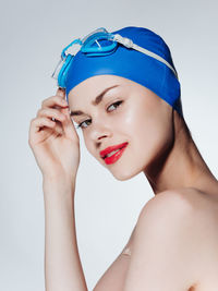 Close-up of young woman applying make-up against white background