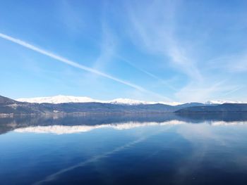 Scenic view of lake and mountains against blue sky