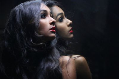 Close-up of young woman against black background