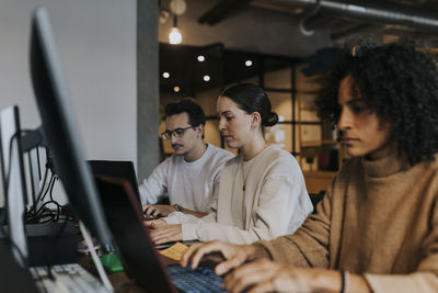 Multiracial male and female hackers working on laptop at creative workplace