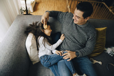 Rear view of couple sitting on sofa at home