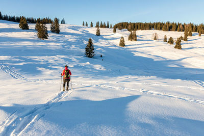 Rear view of woman skiing on snow covered land during winter