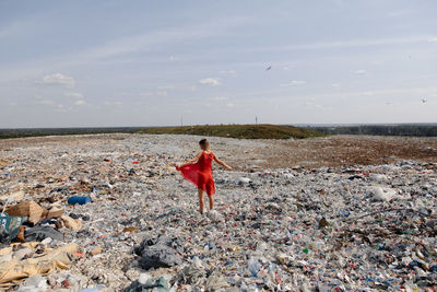 Young woman standing on garbage against sky