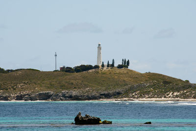 Lighthouse by sea against sky