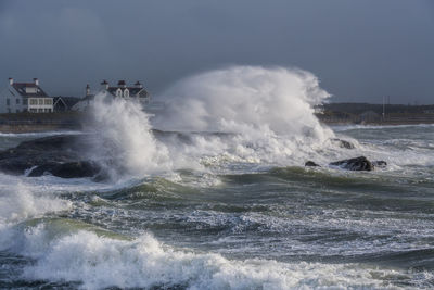 Waves splashing on shore against sky