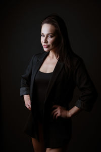 Beautiful young woman standing against black background