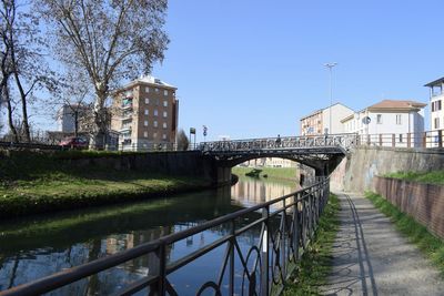 Bridge over river by buildings against sky