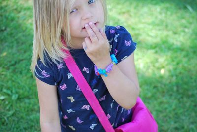 Portrait of cute girl with fingers on lips standing on grassy field at park