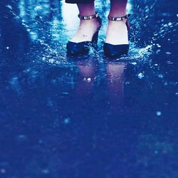 Low section of woman standing on wet puddle