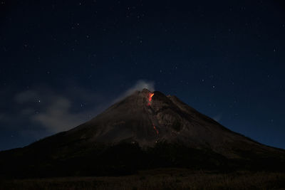 Low angle view of volcanic mountain against sky at night