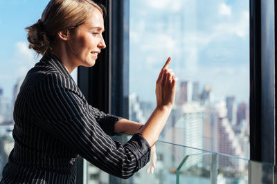 Side view of woman looking through window