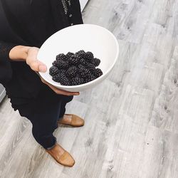 Low section of woman holding blackberries in bowl