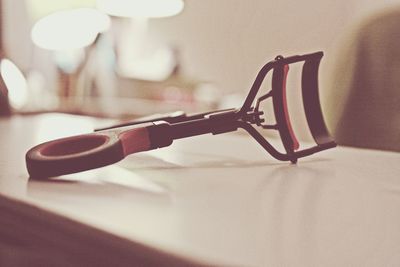 Close-up of eyelash curler on table