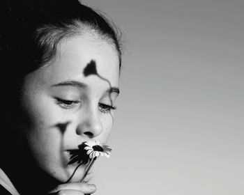 Close-up of girl holding flower against gray background