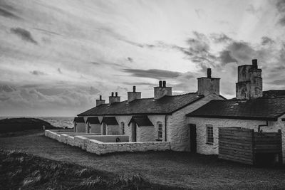 Buildings by sea against sky at sunset