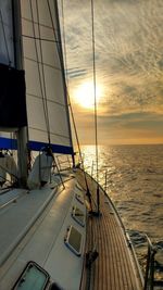 Sailboat sailing on sea against sky during sunset