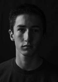 Close-up portrait of young man against black background