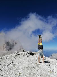 Rear view of man standing on mountain against sky