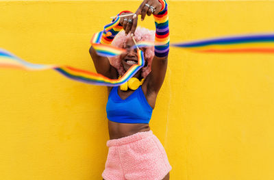 Full length of young woman standing against yellow wall