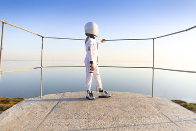 Rear view of woman standing by railing against sky