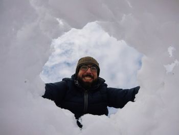 Portrait of man looking through snow against sky