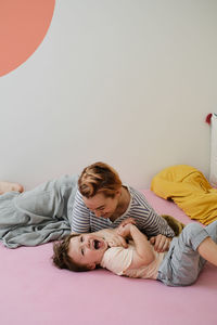 Mother having fun with son on bed. mom and toddler playing, tickling a child, laughing in the