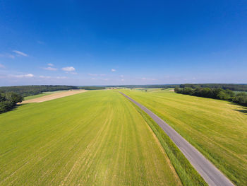 Scenic view of agricultural field against blue sky