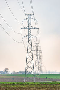 Low angle view of electricity pylon on field against sky