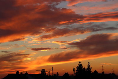 Low angle view of silhouette trees against dramatic sky