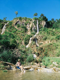 People sitting on rock by river