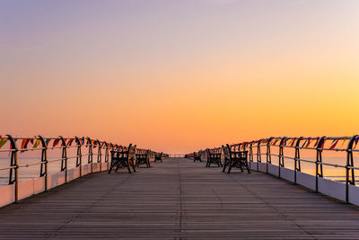 Boardwalk against sky during sunset