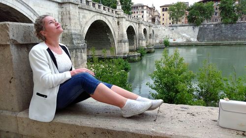 Woman sitting on bridge over water