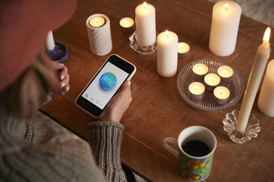 Woman lighting candles and using temperature app