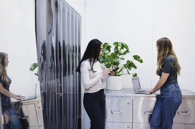 Side view of female bloggers using laptop and smart phone in creative office