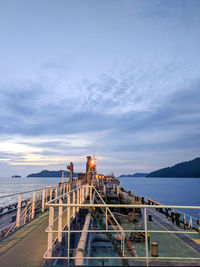 People by sea against sky during sunset