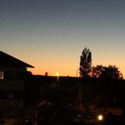 Silhouette trees and buildings against sky during sunset