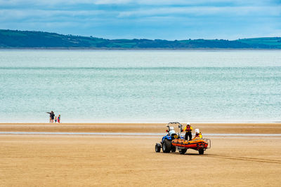 People on beach by sea against sky