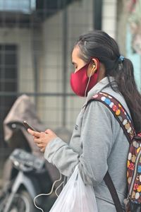 Side view of woman holding mobile phone